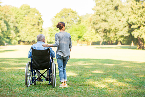 Senior man sitting on a wheelchair with caregiver